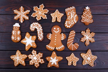 Christmas or New Year background with gingerbread cookies, gingerbread man cookies, stars, snowflakes and decorations flat lay on wooden table. Winter holidays concept. Festive food background