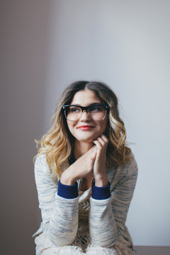 A young woman in a seated position leaning forward smiling