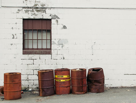 Rusty oil drums by a brick wall