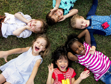 Group of kindergarten kids lying on the grass at park and relax with smiling