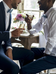 Gay couple having champagne at wedding reception
