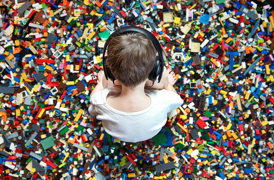 Boy wearing headphones sits surrounded by colorful stacking blocks