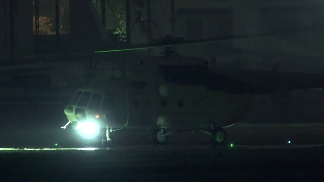 Civil helicopter with the searchlight on unfolds on the runway at night