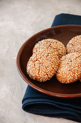 Homemade oatmeal cookies with sesame seeds in a plate on a white stone background