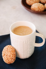 A cup of latte with cookies. White stone background.