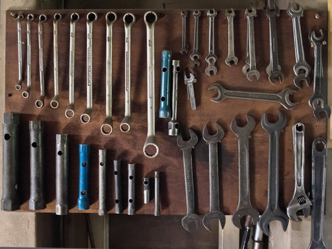 different sized wrenches sorted on a board in a workshop