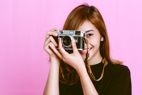 Fashion photo of young girl taking picture with camera on pink background