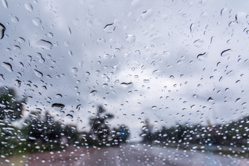 Water drop on glass with road and tree In the rain.