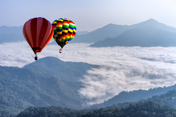 Hot air balloon with tourist is traveling into the peak of mountain and cloudscape at Doi Pha Tang in Chiangrai Provice, Thailand