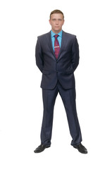 Business man stands holding his hands behind his back isolated on white background.