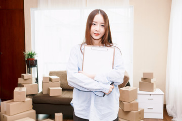 Young woman checklist with cardboard box at home - Business online and delivery concept