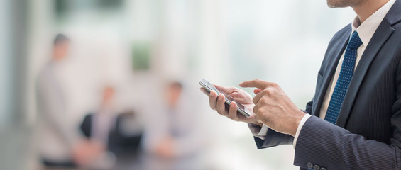 Businessman using smart phone in blurred office space background and copy space.Concept of business...