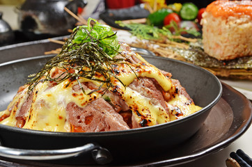 Tasty risotto with baked beef, kimchi and cheese on a black pan