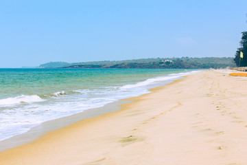 Tropical sandy beach of the sea with waves and sunny sky.