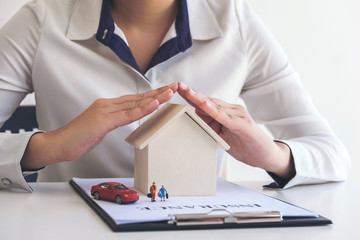 insurance and care protection of house family concept, woman with protective gesture of small home, people and car model