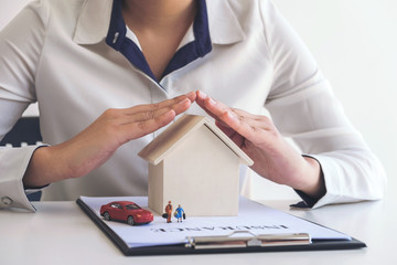 insurance and care protection of house family concept, woman with protective gesture of small home,...