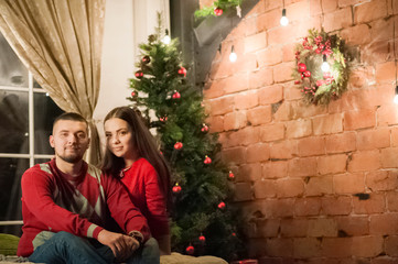 Beautiful happy young family celebrating Christmas together. Lovers on the New Year together in an apartment in the Loft style. Bedroom apartment Loft decorated in New Year's style.