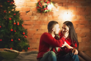 Beautiful happy young family celebrating Christmas together. Lovers on the New Year together in an apartment in the Loft style. Bedroom apartment Loft decorated in New Year's style.