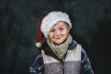 Portrait of a boy in the Santa hat . Evening walks under the snow