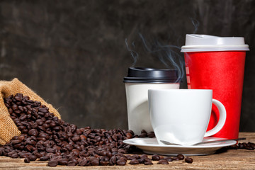 Cups of coffee with smoke and coffee beans