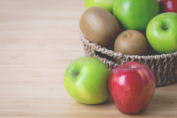 Fresh fruits in a basket on a wooden background .