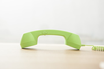 green phone on the wood desk(table) at the day light.