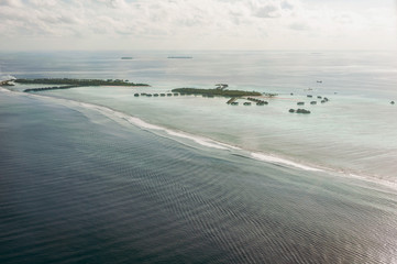 Tropical islands and atolls in Maldives in Indian Ocean from aerial view. Piece of paradise on the Earth. Good choice for vacation. Beautiful top view for wallpaper.