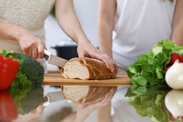 Close-up of human hands slicing bread in a kitchen. Friends having fun while cooking in the kitchen. Chef cook represent culinary masterclass