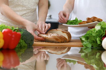Close-up of human hands slicing bread in a kitchen. Friends having fun while cooking in the kitchen. Chef cook represent culinary masterclass