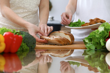 Close-up of human hands slicing bread in a kitchen. Friends having fun while cooking in the kitchen. Chef cook represent culinary masterclass