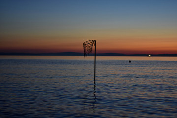 Basketball hoop in the sea whit beautiful sunset scenery