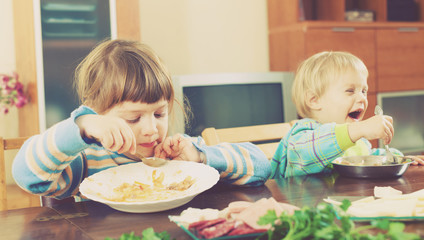 Obraz na płótnie Canvas happy baby girls eating at table