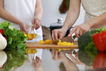 Close-up of  human hands  cooking in a kitchen. Friends having fun while preparing fresh salad. Vegetarian, healthy meal and friendship concept