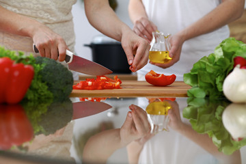 Close-up of  human hands  cooking in a kitchen. Friends having fun while preparing fresh salad....