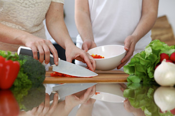 Obraz na płótnie Canvas Close-up of human hands cooking in a kitchen. Friends having fun while preparing fresh salad. Vegetarian, healthy meal and friendship concept