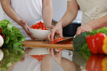 Close-up of  human hands  cooking in a kitchen. Friends having fun while preparing fresh salad. Vegetarian, healthy meal and friendship concept