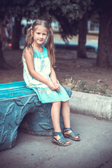 Naklejka premium Portrait of a little girl in the park on a bench