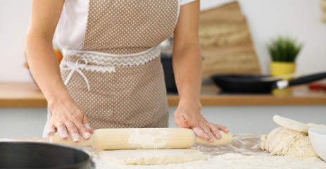 Female hands making dough for pizza or bread while using rolling pin. Baking concept