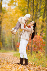 Fototapeta premium Little girl and her mother playing in the autumn park