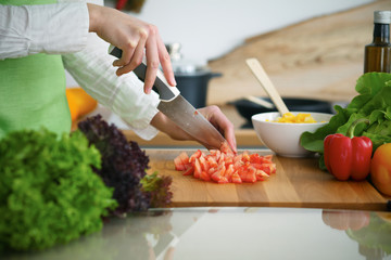 Closeup of human hands cooking vegetables salad in kitchen on the glass  table with reflection