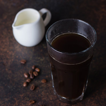 A glass of hot coffee espresso on dark background with coffee beans