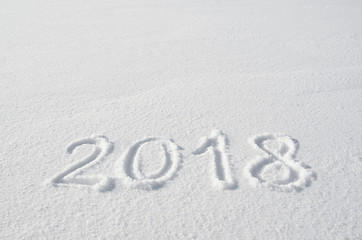 2018 text letters handwritten on flat snow surface. New year holiday seasonal postcard, greeting card template.