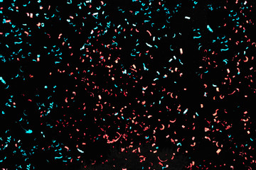 Confetti fired in the air during a beach party. Only confetti on black background of the night....