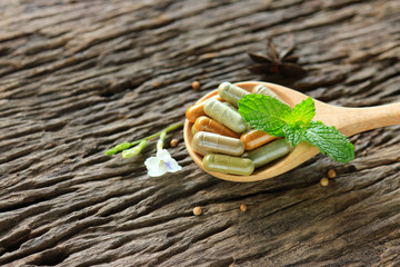 Herbal capsules from herb on wooden spoon with herbal tree