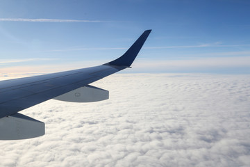Obraz premium Wing of airplane flying above the clouds