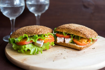 Delicious sandwiches with chicken and tomatoes for breakfast. Tasty snack of poultry and vegetables for lunch. Water in a glass