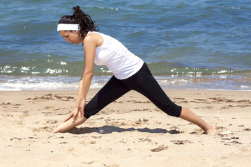 Young woman stretching by the beach
