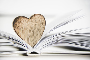 wooden heart shape on a open book. Love reading concept close up.