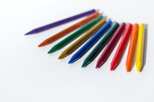 A row of colorful crayon pencil on white background with blank space.