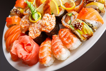Maki, uramaki and nigiri sushi served in white plate close up